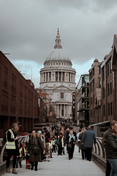 During the day, people walking on the streets of the brown concrete buildings nearby
